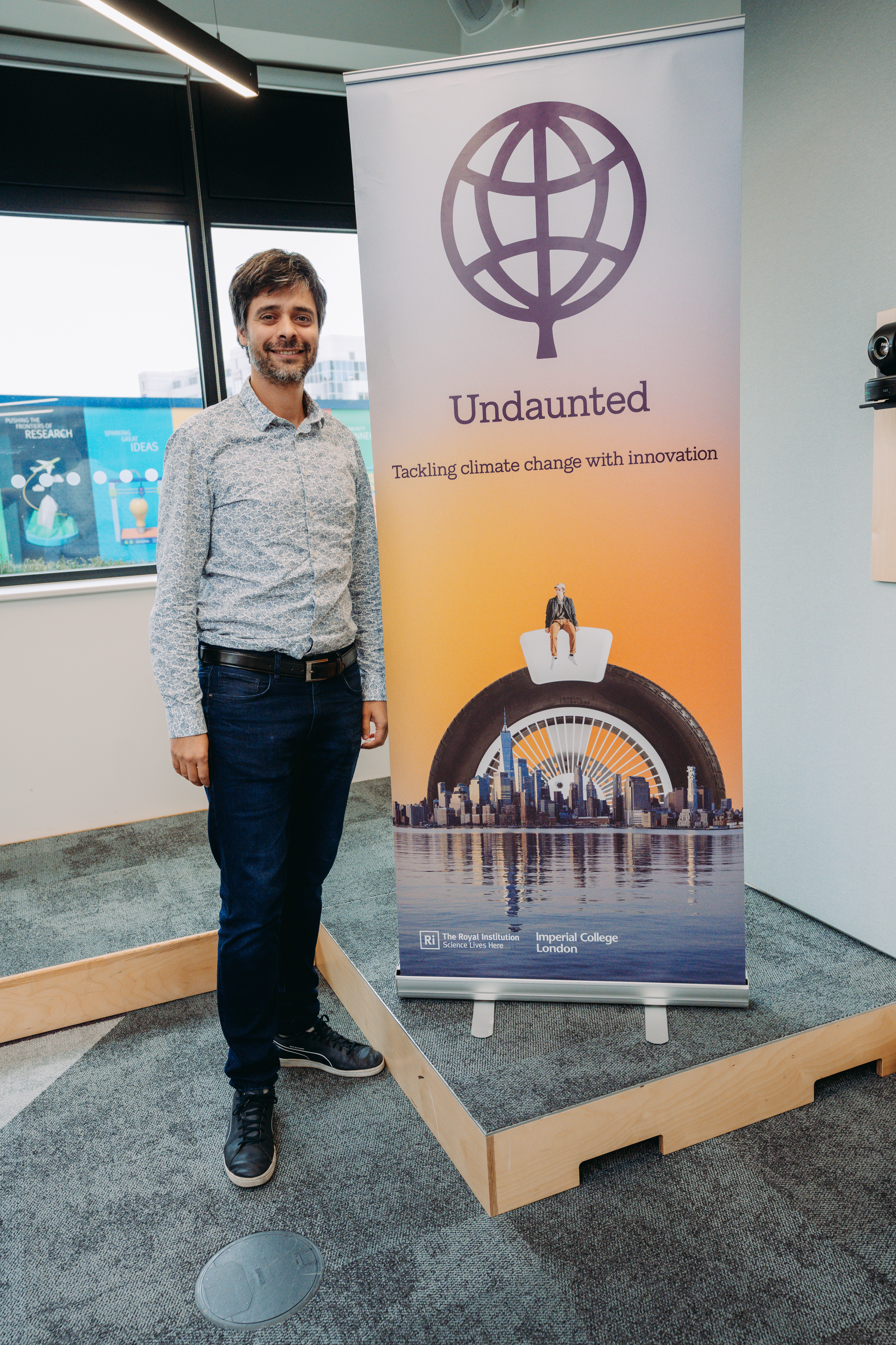 Man standing in front of a standee with Undaunted's banner logo. Matias Acosta, CEO, Cosysense at the Better Futures Retrofit Accelerator's Challenge Identification Workshop. Photo by Velvet Green Media